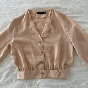 This a a peach colored fitted blouse